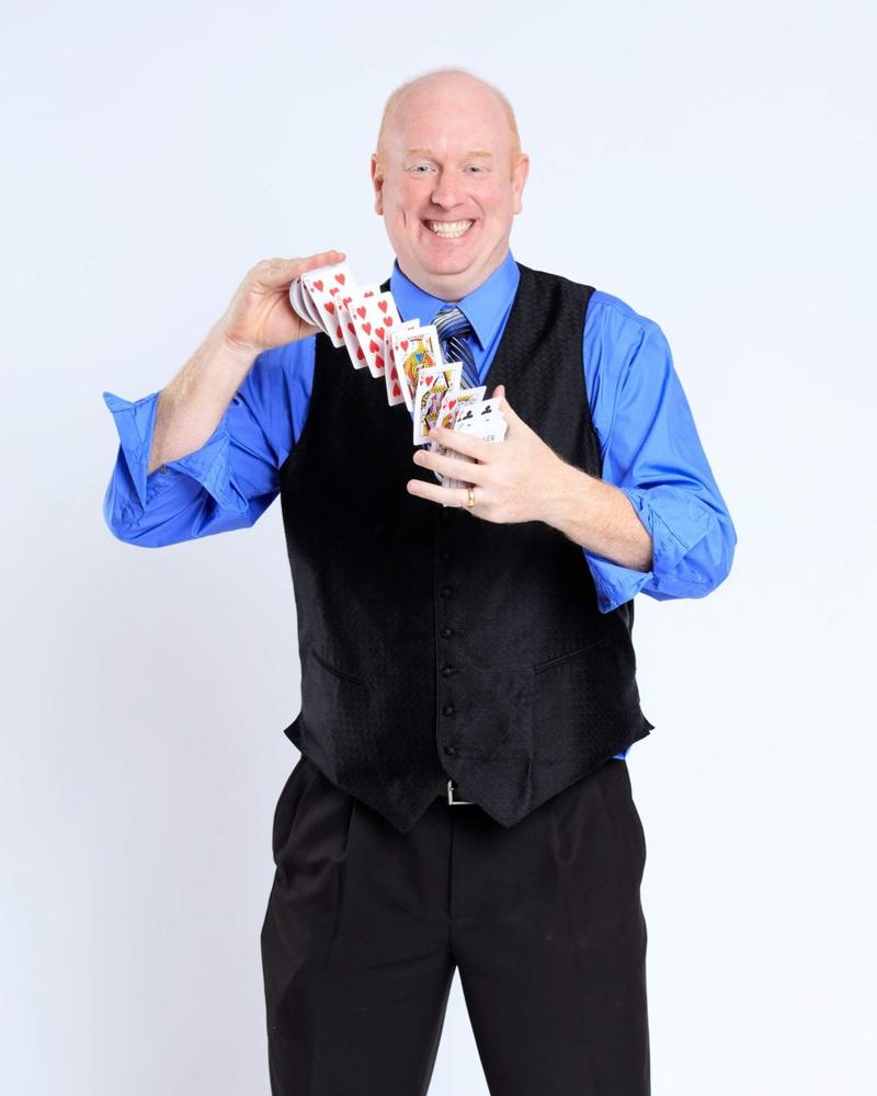 Scott Henderson, Kansas City magician, studio portrait with cards in mid-flourish