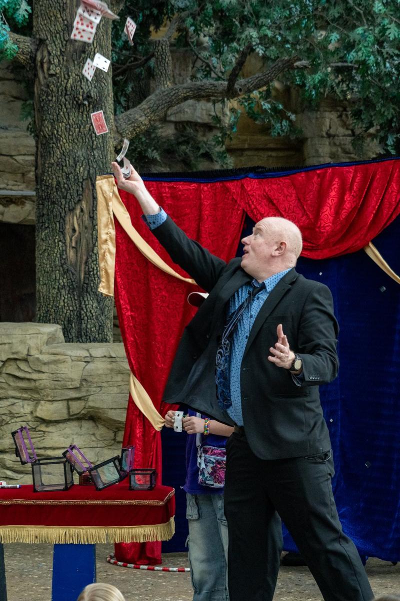 Scott Henderson tossing a deck of cards into the air on stage