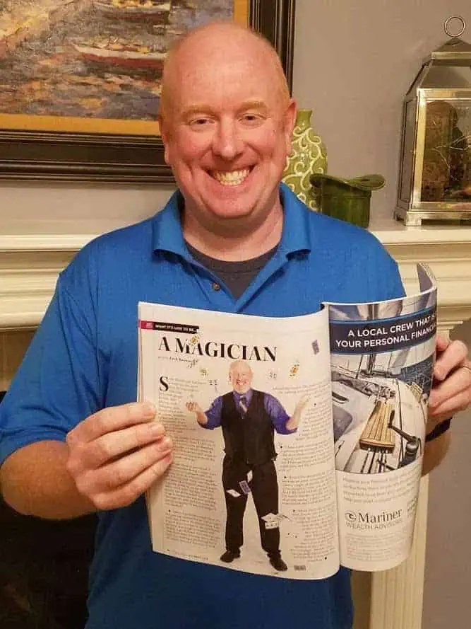 Scott Henderson at home holding the 435 Magazine issue containing his feature, smiling at the camera