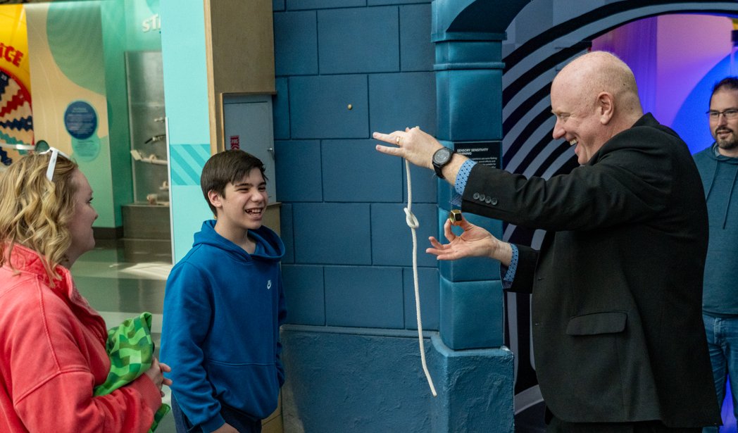A young volunteer at Science City Kansas City, mid-routine with Magic Scott — the kind of family-event reaction that lasts