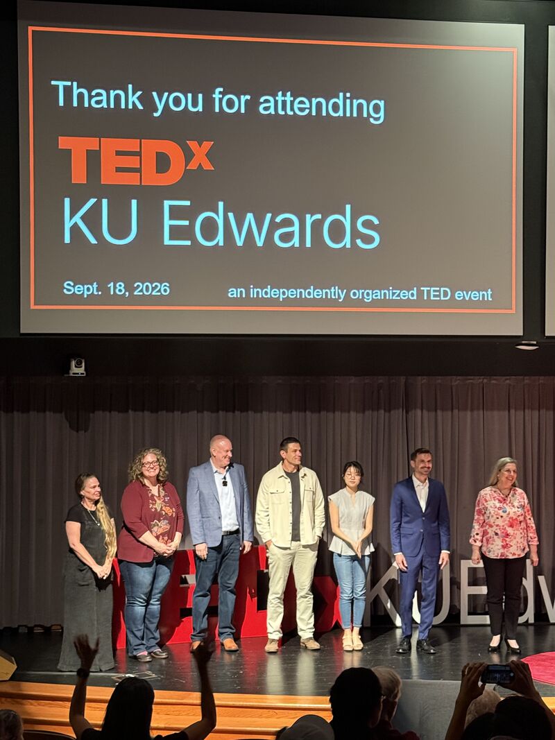 Scott Henderson (third from left, gray blazer) with the full TEDxKUEdwards 2026 speaker lineup on stage after the event
